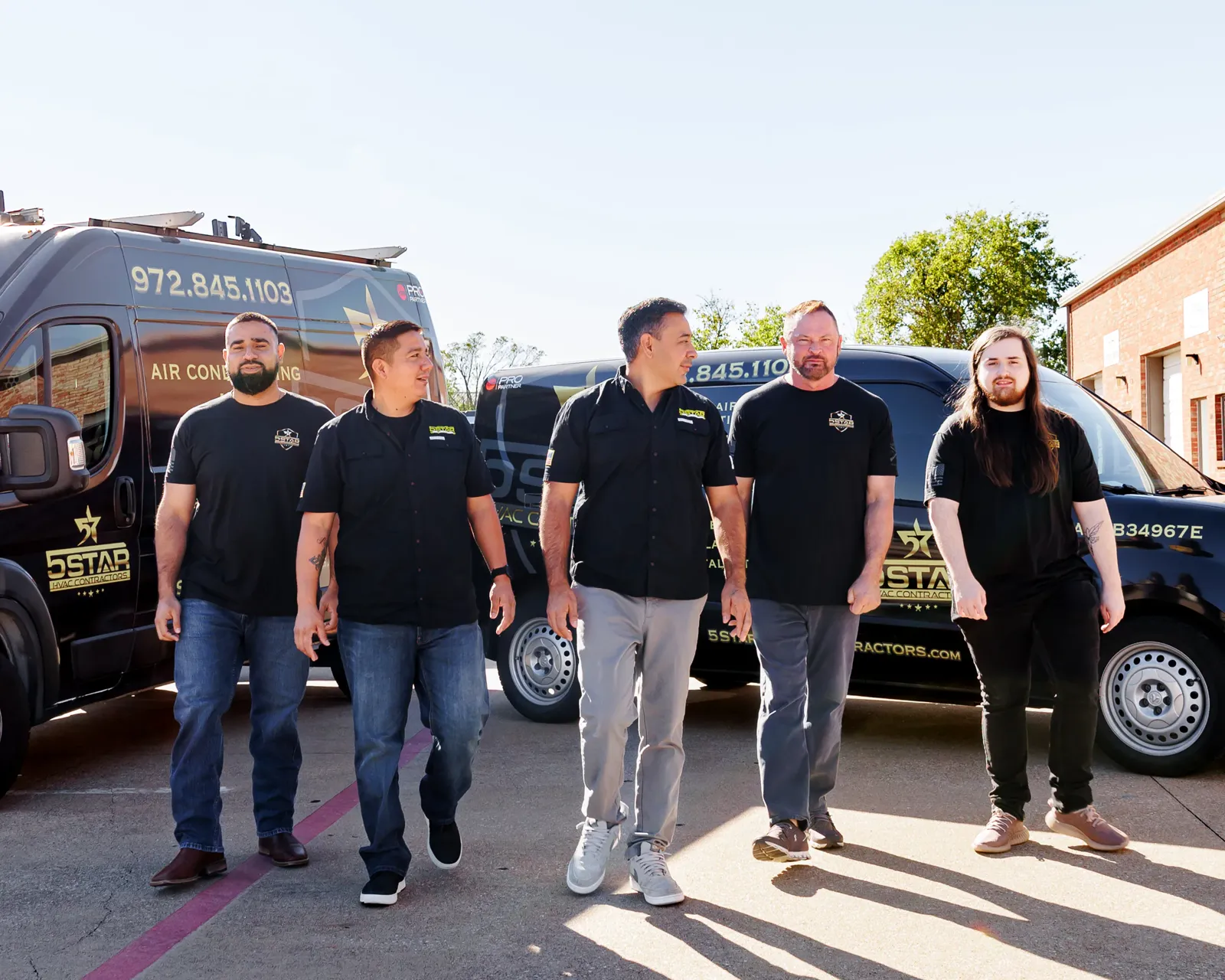 The 5 Star HVAC Contractors team walking in front of company service vehicles